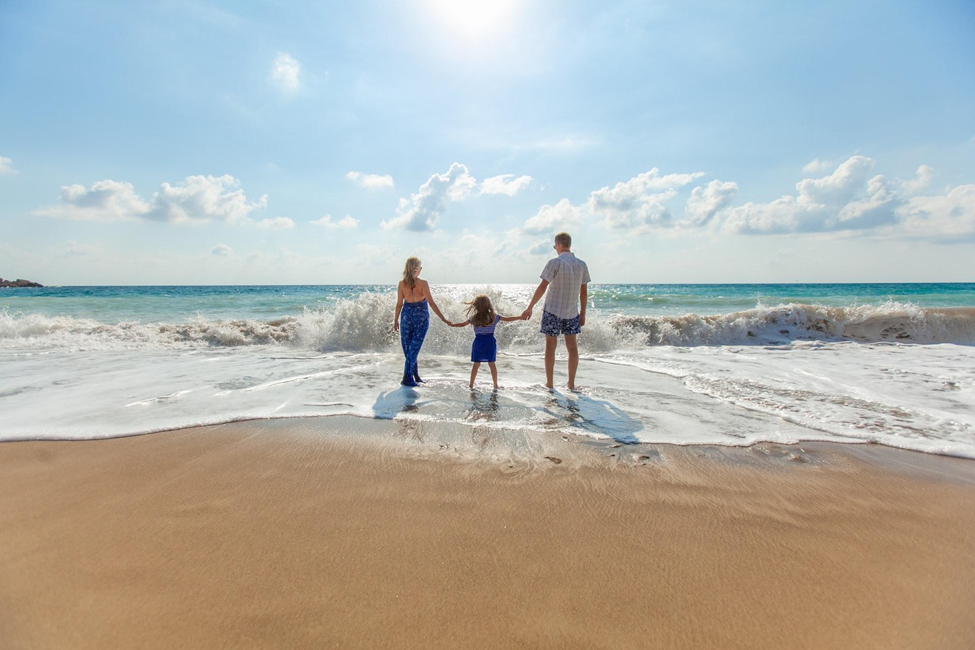 A family playing in the ocean waves at a beach representing the family-friendly vacations travelers take with Royal Holiday Vacation Club.